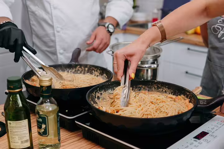 Participants cooking pasta in a hands-on class during the Vatican Market Experience, featuring authentic Italian ingredients.