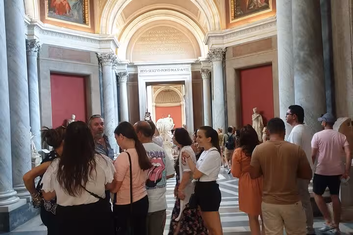 Tourists admire classical sculptures and art in the grand halls of the Vatican Museum on a guided fast track tour.
