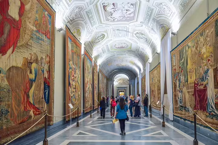 Visitors walking through the Vatican Museums tapestry gallery on a guided group tour to the Sistine Chapel in Rome, Italy