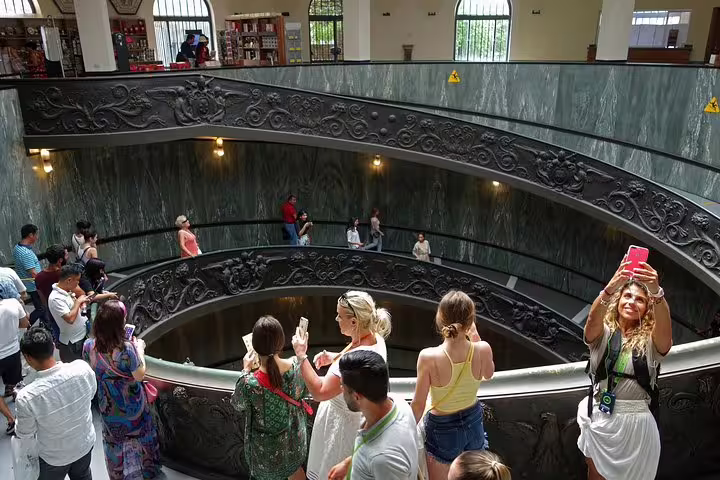Visitors on a Vatican Museums guided tour admire the ornate spiral staircase before entering the Sistine Chapel group experience