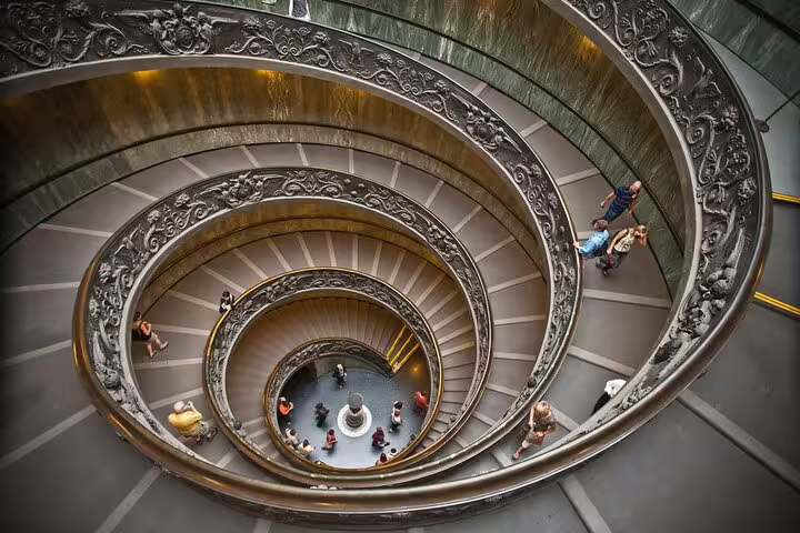 Tourists walk down the ornate double spiral staircase in the Vatican Museums during an exclusive Rome private VIP tour
