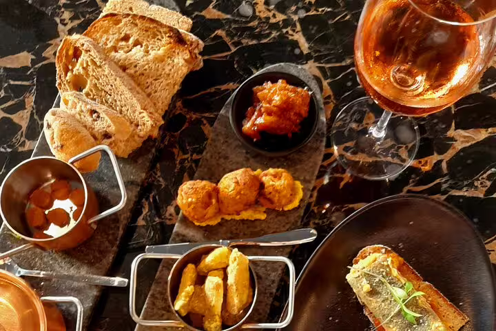 Delicious vegan-friendly tapas with a glass of rosé wine on a marble table during a food and walking tour.