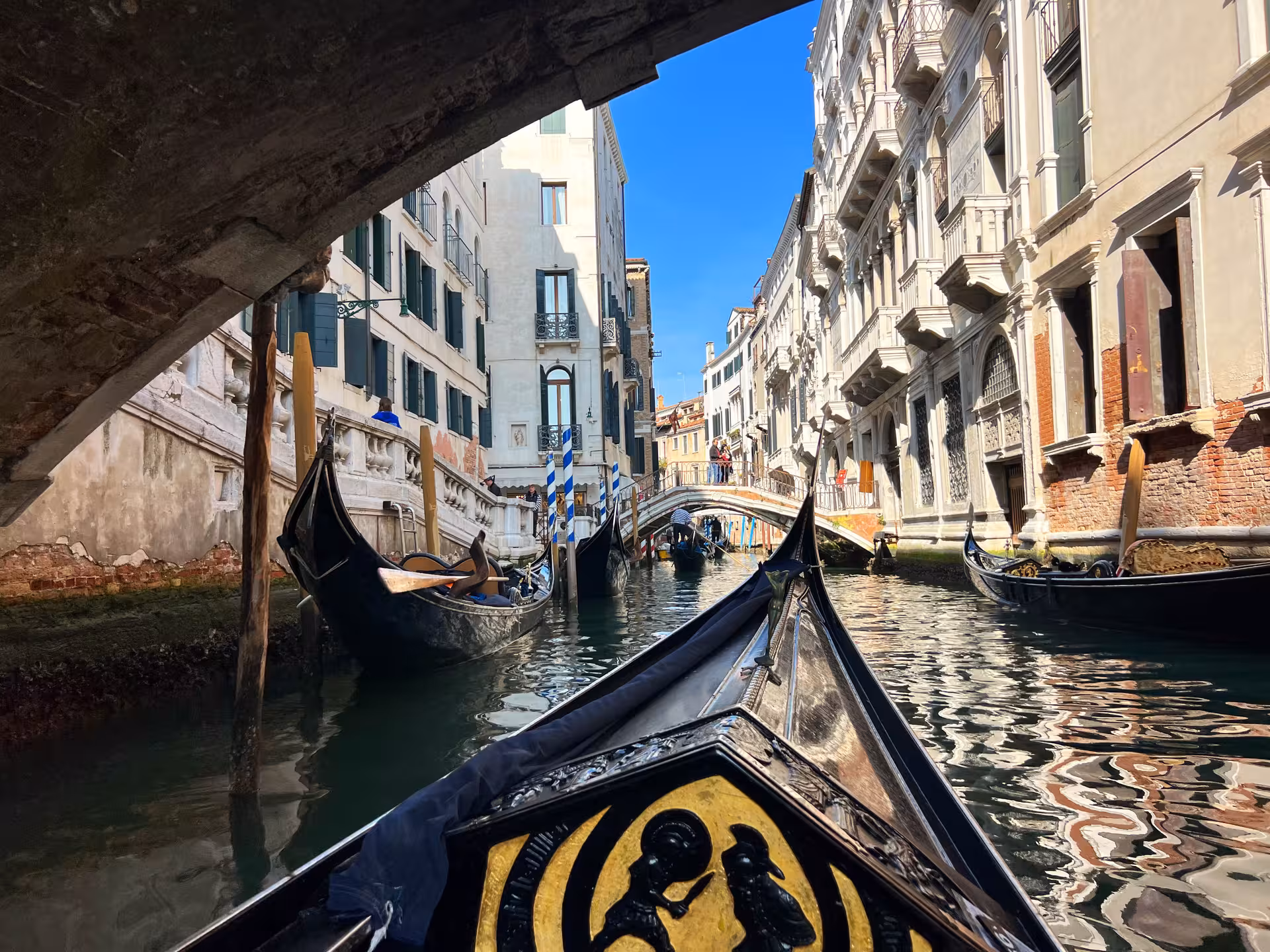 Gondola gliding through a picturesque Venetian canal under an arched bridge, showcasing historic architecture.