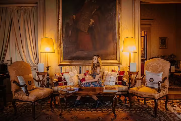Elegant interior of a Venetian palace with a woman seated on a lavish sofa, surrounded by classic decor and warm lighting.