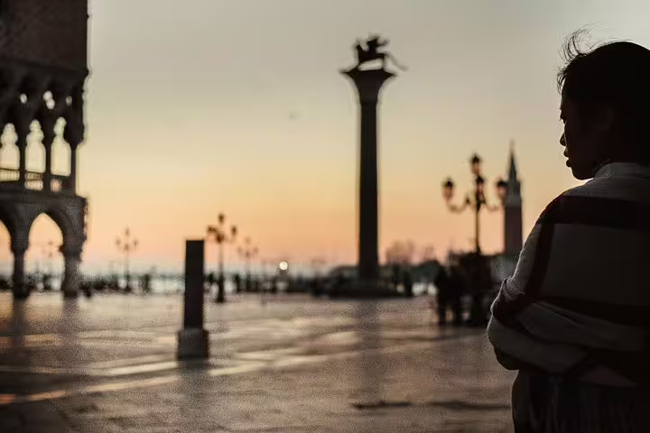 Silhouetted woman gazing at a serene Venetian sunrise, perfect for an early morning photo tour and luxury breakfast.