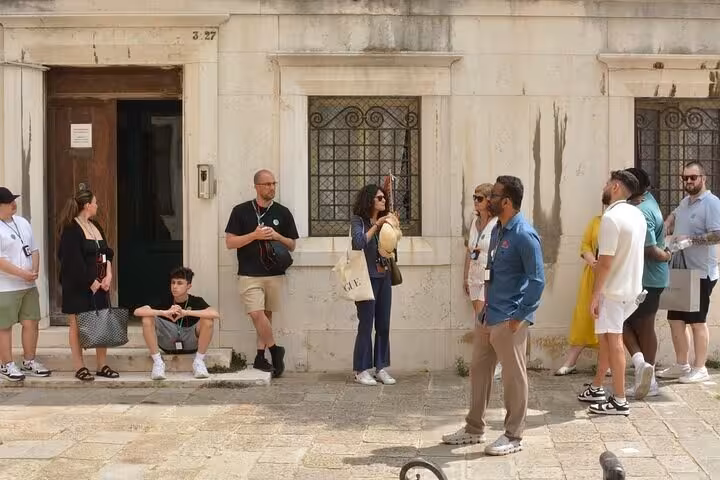 Tourists gather in a historic Venetian square, engaging in a small group walking tour experience.