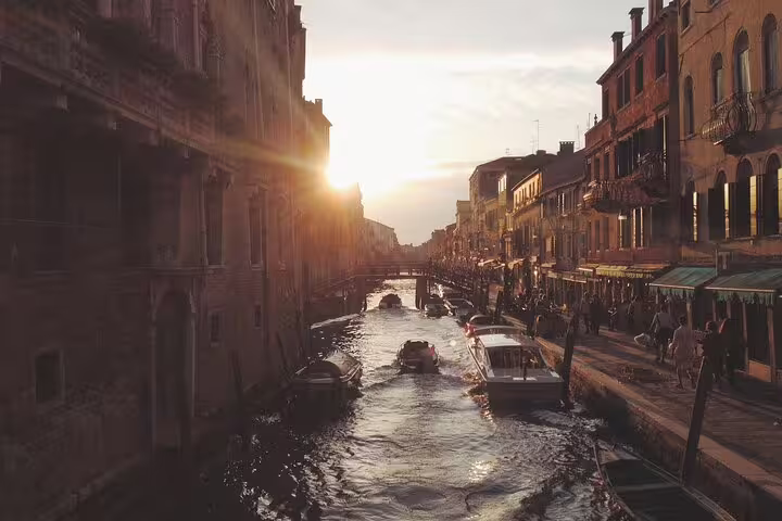 Sunset over a lively Venice canal with boats and historic palazzi, ideal for a last minute private evening tour