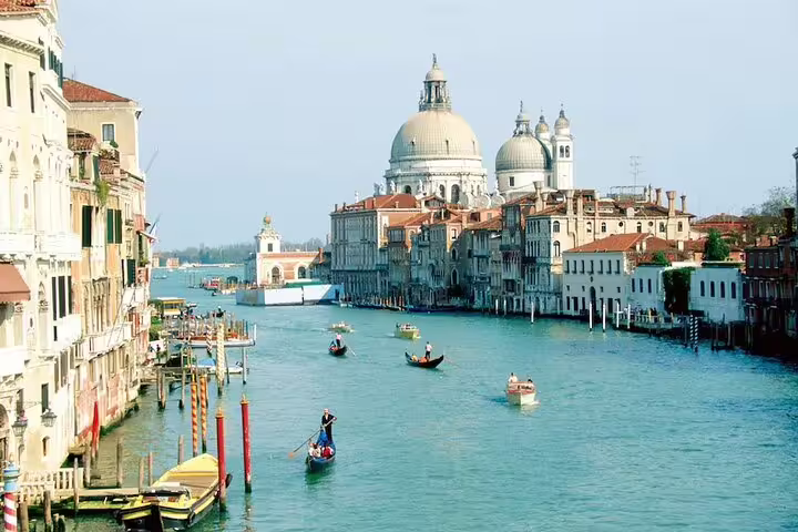 Gondolas cruising the Grand Canal toward Santa Maria della Salute, showcasing classic Venice landmarks on a private boat tour