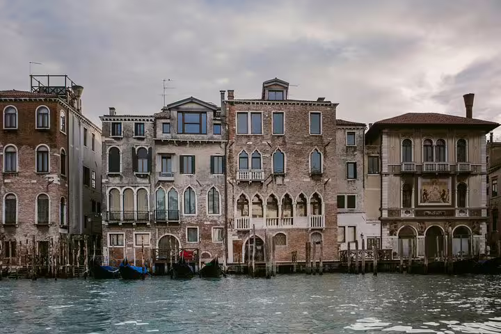 Historic Venetian buildings line the Grand Canal, showcasing stunning architecture and gondolas at the water's edge.