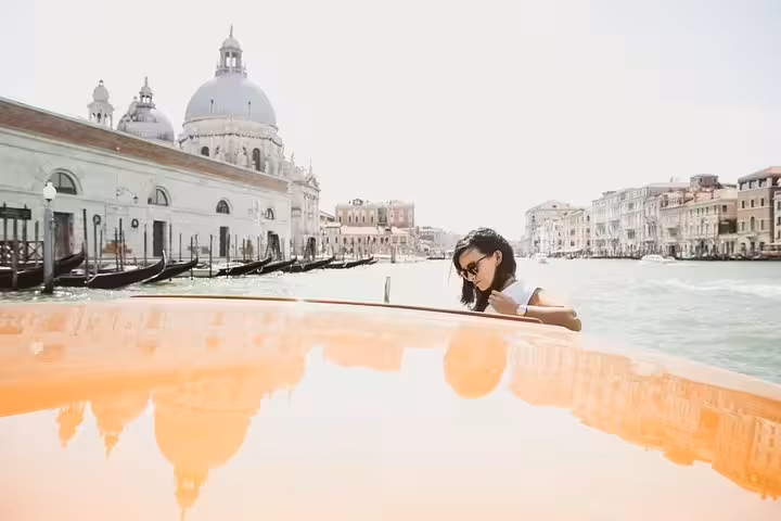 Woman enjoying a scenic boat ride on Venice's Grand Canal with historic architecture in the background.