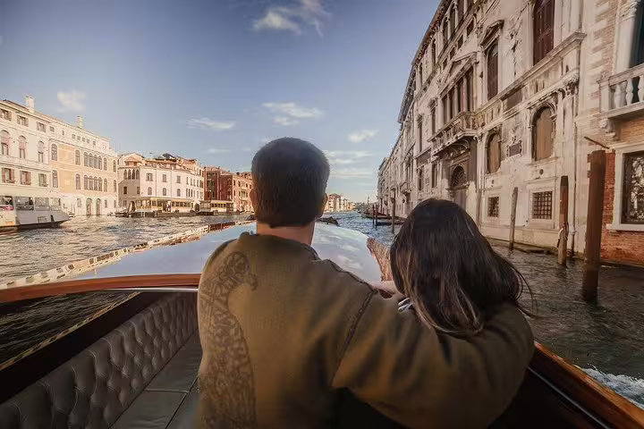 Couple enjoying a romantic boat ride on the Venetian Grand Canal surrounded by historic architecture.