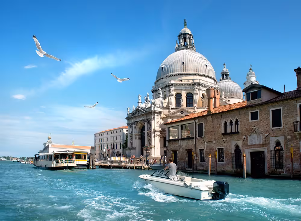 Scenic view of Venice Grand Canal with boats and historic architecture near St Mark's Basilica under a clear blue sky.