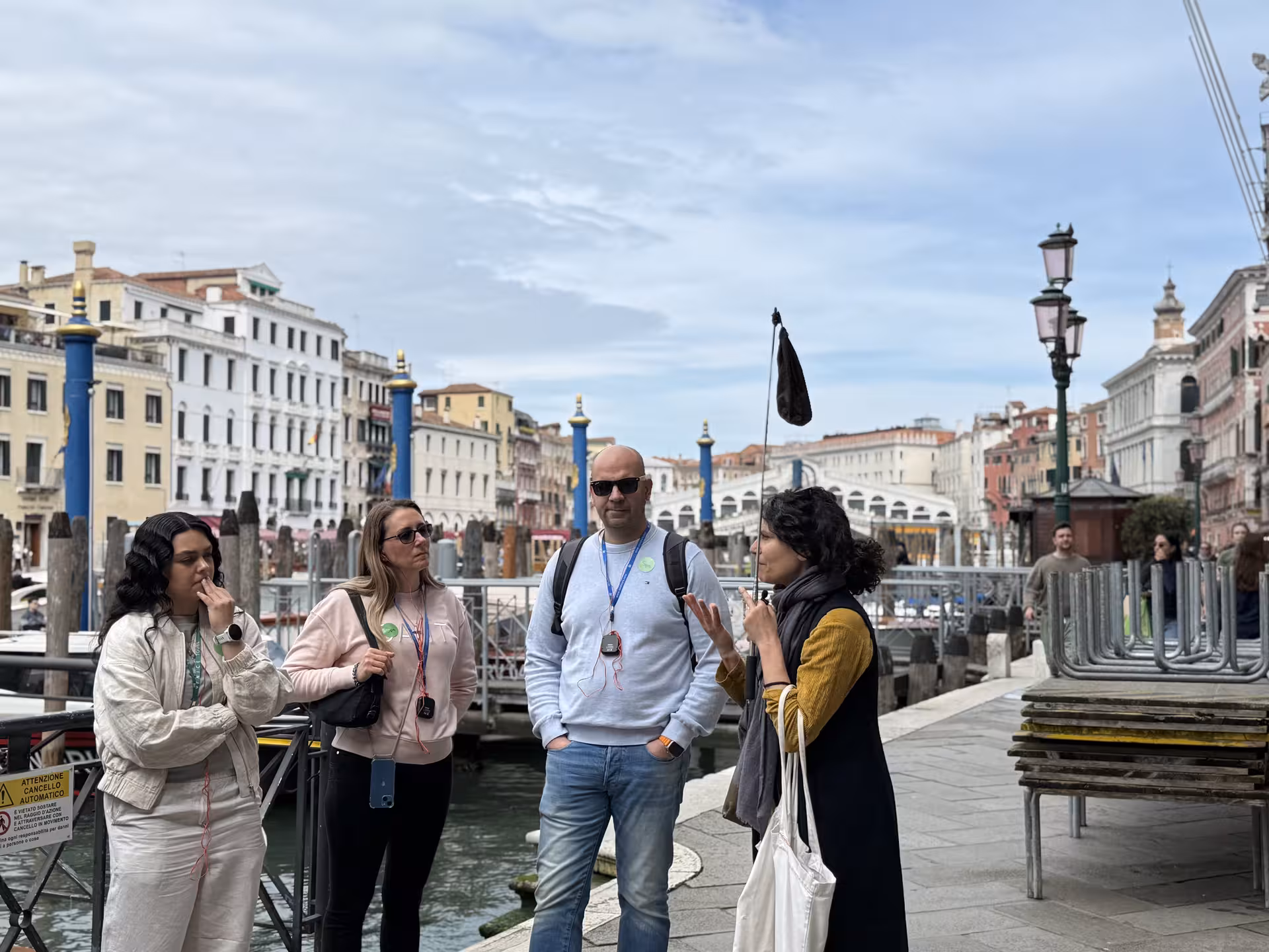 Tour guide with travelers by the Grand Canal, experiencing Venice like a local with a spritz in hand.