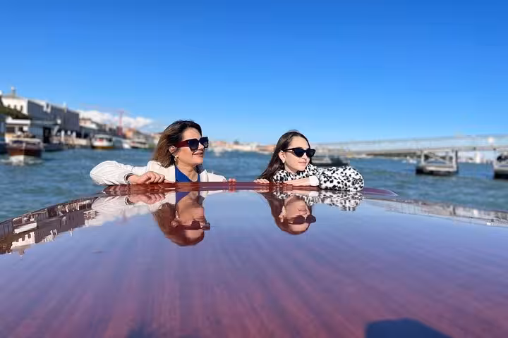 Women leaning on a boat admiring the Venetian skyline during a private transfer from Marco Polo Airport.