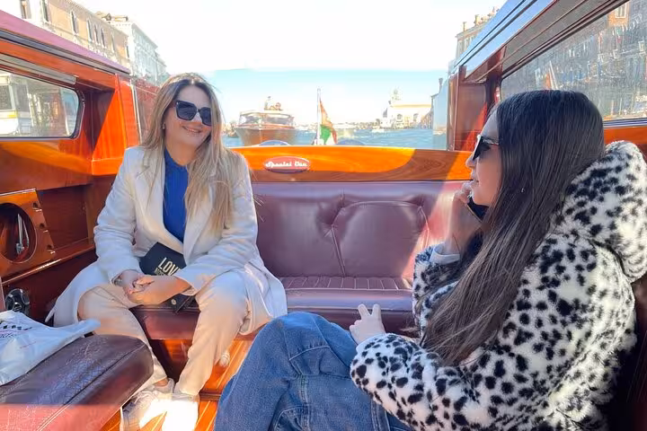 Two women enjoying a private water taxi ride in Venice, part of the Marco Polo Airport transfer experience.