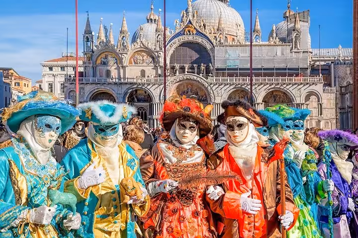 Colorful masked performers in front of St. Mark's Basilica, capturing Venice's vibrant culture on a day trip from Florence.