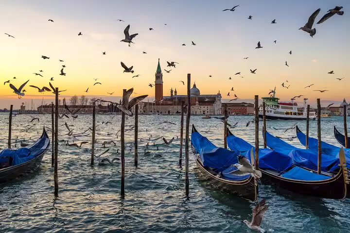Private Venice gondola ride at sunset with moored boats, San Giorgio Maggiore and lagoon views on hidden canals tour