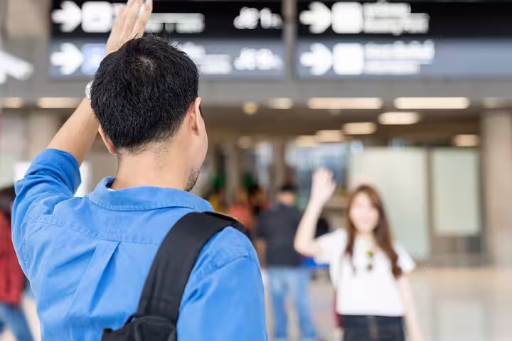 Man waving goodbye at airport, symbolizing the start of a private transfer journey from Venice to Ravenna cruise terminal.