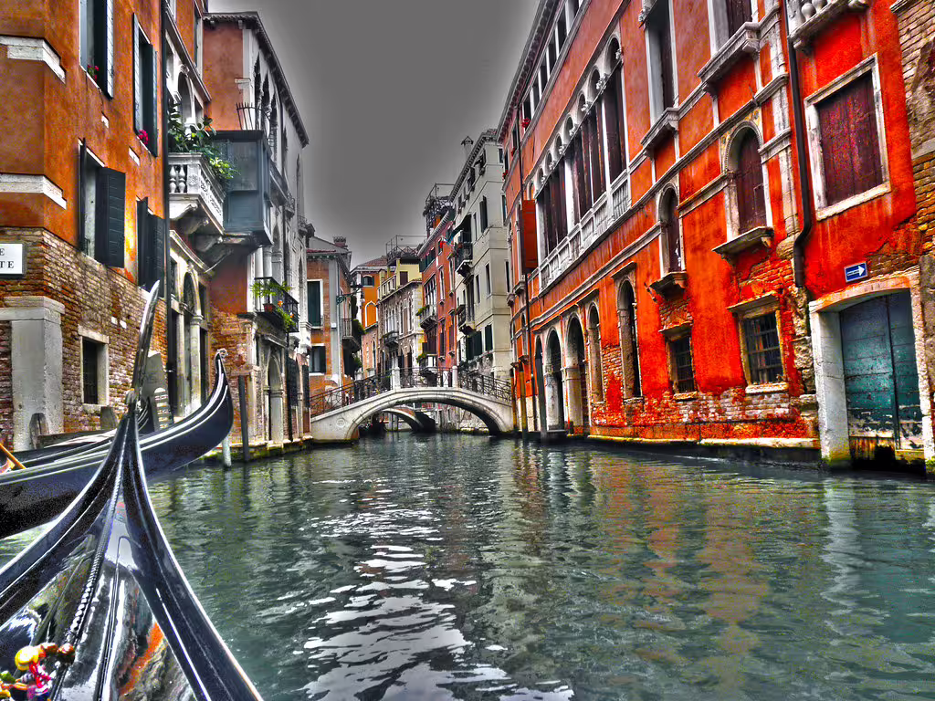 Gondola ride through a quiet Venice canal lined with colorful palazzi and arched stone bridge on a romantic city break