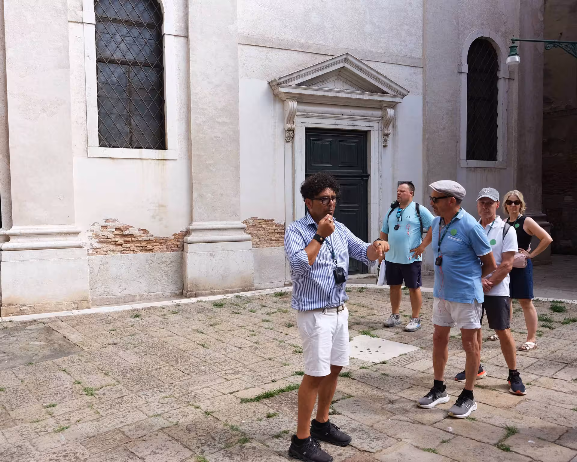 Guide leading a group tour in Venice, highlighting historic architecture on the San Marco to Rialto walk.