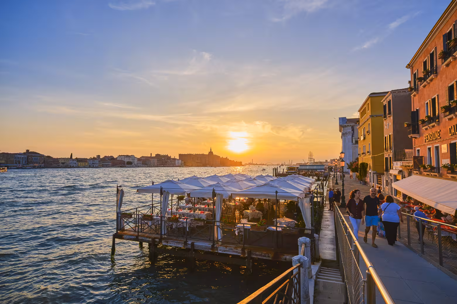Sunset dining experience on Venice's waterfront with vibrant colors and stunning canal views.