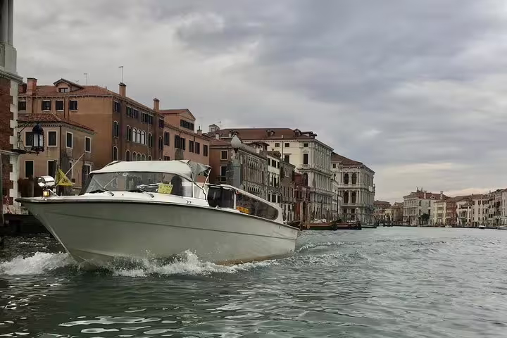 Elegant white water taxi cruising Venice's Grand Canal for private hotel to VCE airport transfer.