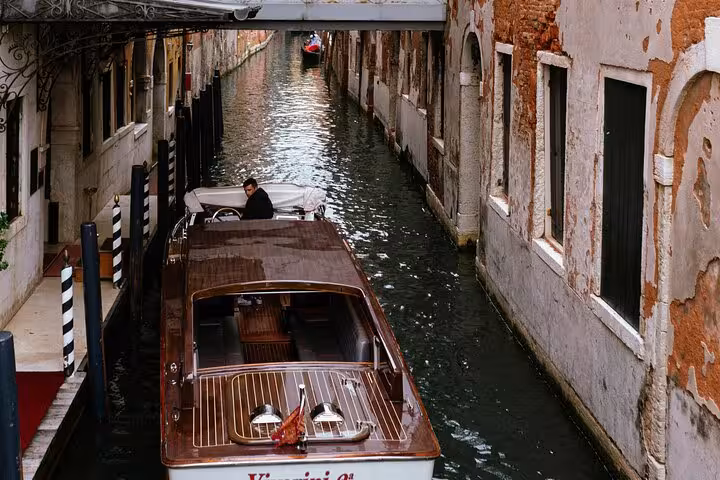 Private water taxi navigating a narrow Venetian canal, showcasing Venice's unique transportation from Marco Polo Airport.