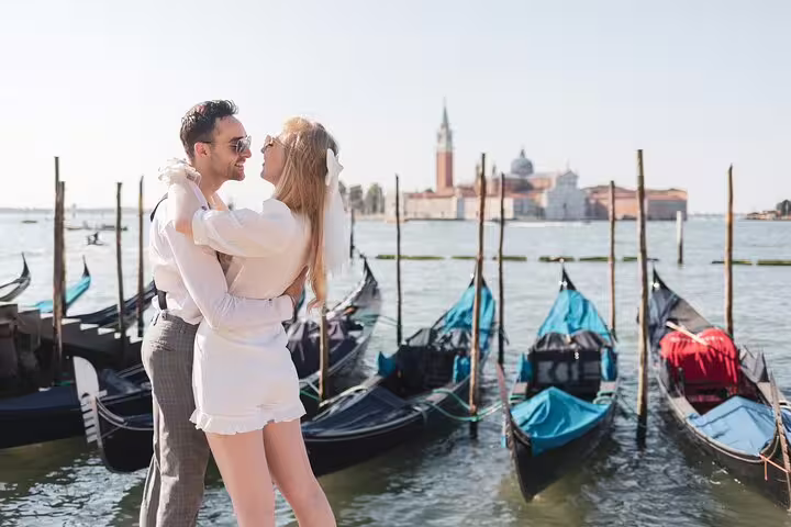 Venice wedding photo shoot with couple embracing by gondolas on the lagoon, romantic Italy elopement