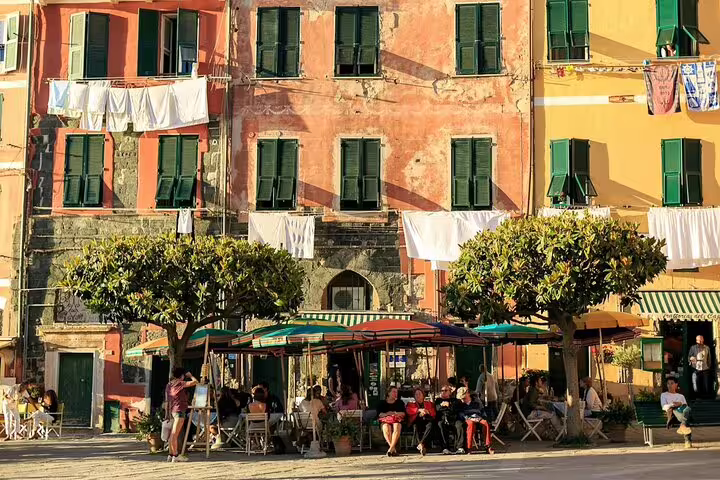 Colorful Vernazza-style piazza in Cinque Terre with café terraces, laundry lines and vibrant Ligurian village life