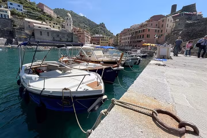 Docked boats in Vernazza's charming harbor, surrounded by colorful buildings and scenic hills in Cinque Terre.