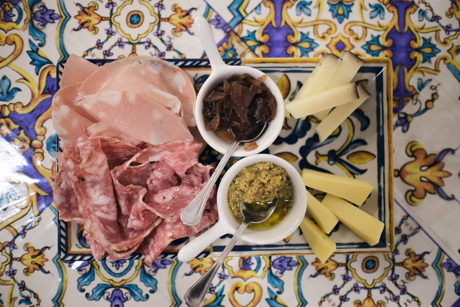 Verona charcuterie board with prosciutto, salami, local cheeses, pesto and chutney on ceramic plate