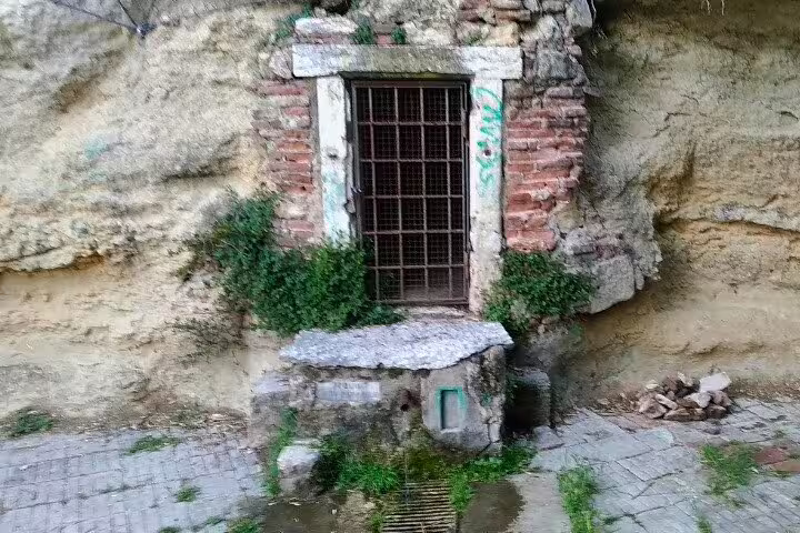Rock-cut doorway with iron grate and brickwork on Verona Hillside guided walking tour of hidden sites