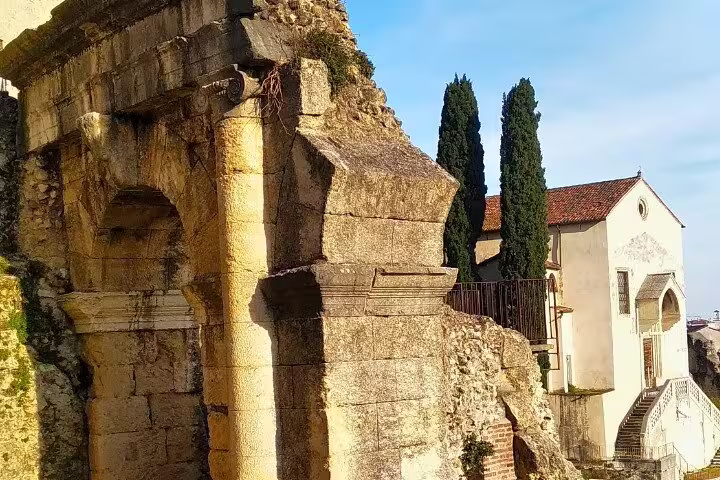 Ancient Roman stone arch and hillside chapel in Verona, a highlight stop on the guided walking tour route