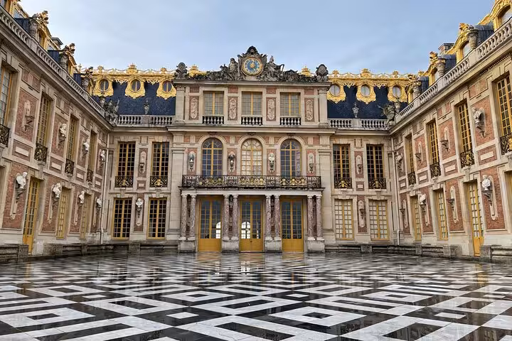 Versailles Grand Tour guided palace courtyard view with ornate facade, gold trim, and checkerboard paving