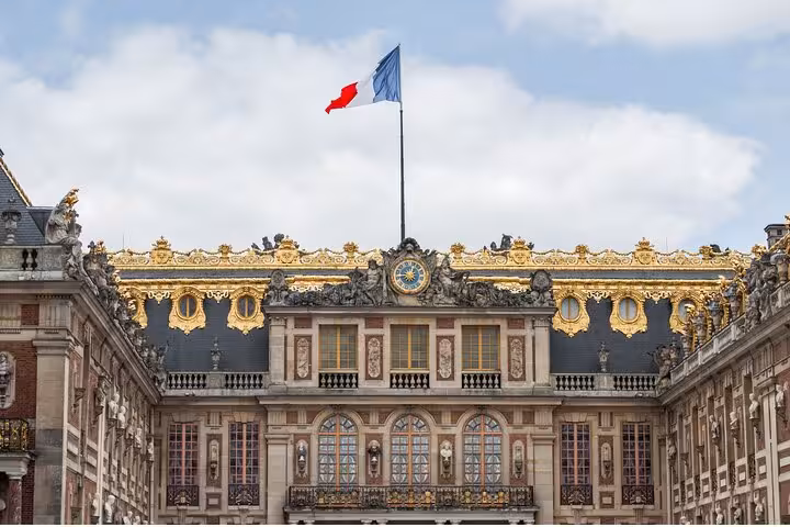 Versailles Grand Tour view of the palace facade with French flag and ornate gold rooftop details