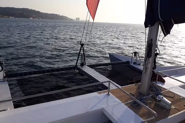 The Vertigo catamaran sails smoothly on Lisbon's waters, offering panoramic views of the coastline and tranquil sea.