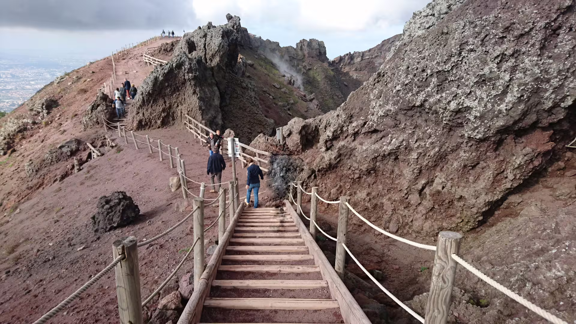 Hikers on the Vesuvius crater trail with wooden steps, part of a low cost Mount Vesuvius tour from Naples
