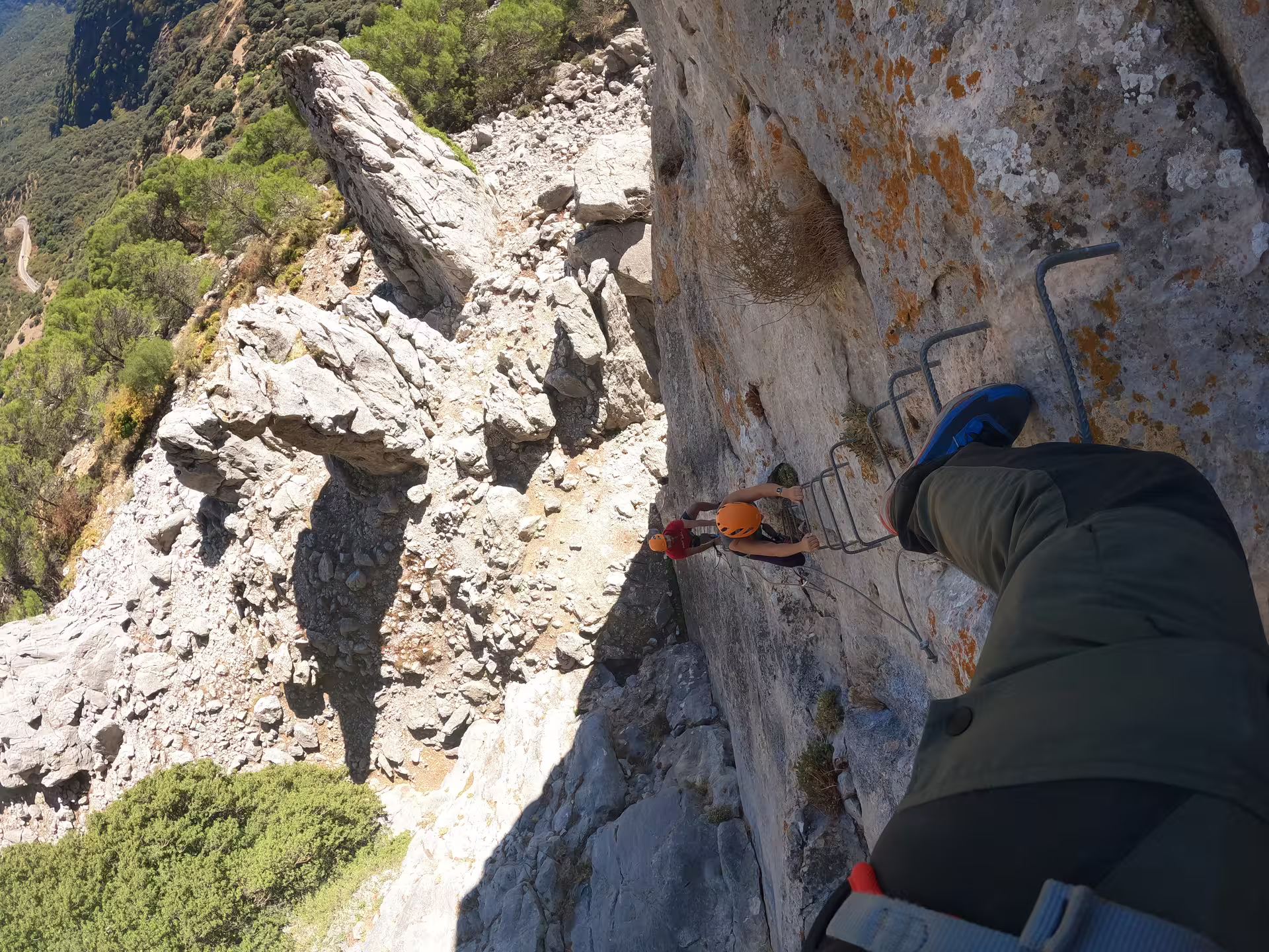 Adventurers climbing Via Ferrata Benadalid, scaling rocky cliffs with safety gear, offering stunning Costa del Sol views.