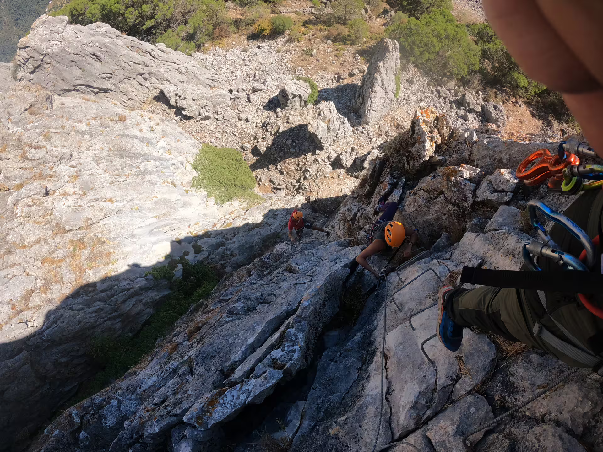 Adventurers climbing steep rocky path on Via Ferrata Benadalid, offering thrilling challenges and stunning Costa del Sol views.
