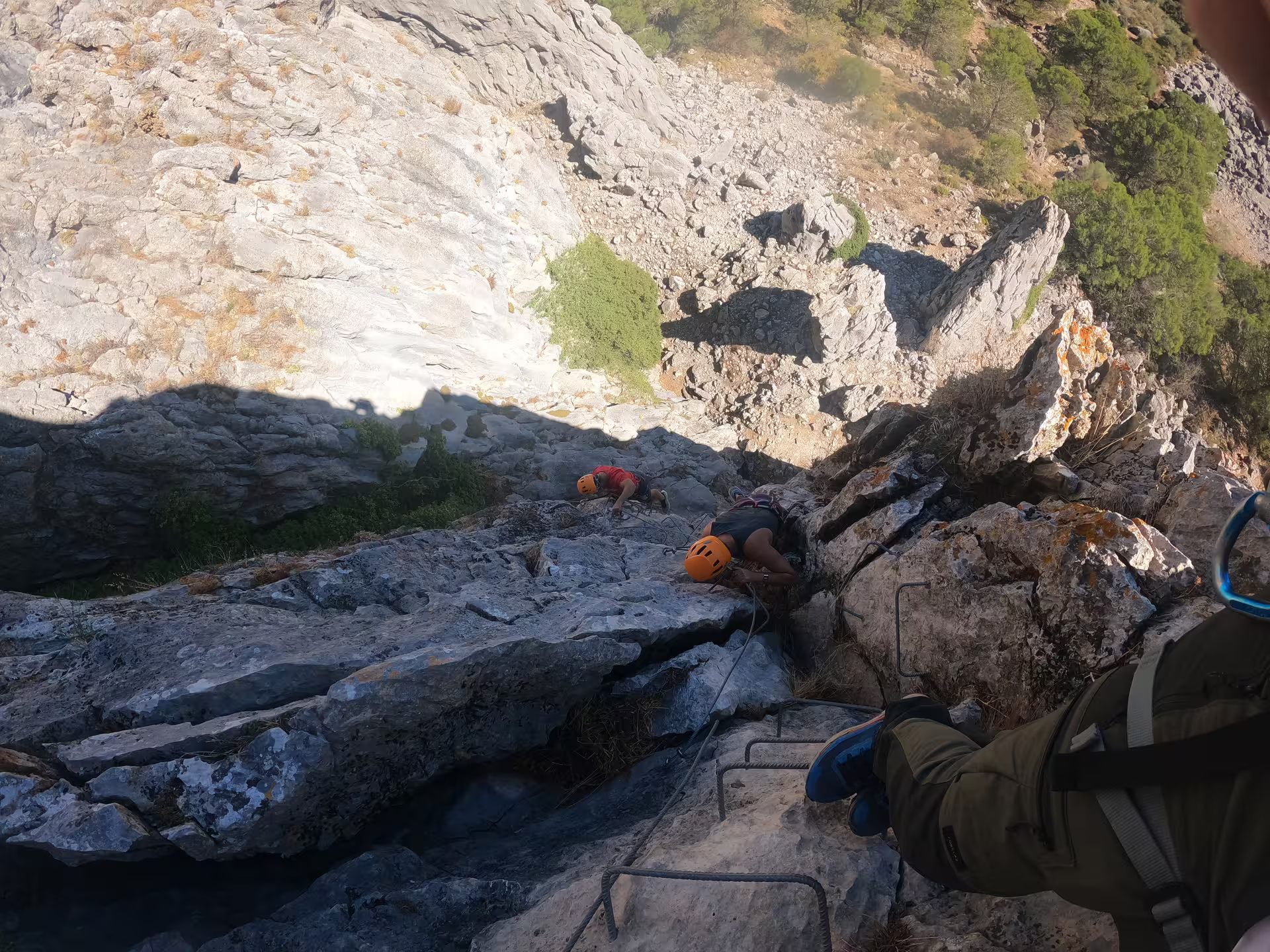 Adventurers climb a rugged Via Ferrata route in Benadalid, Spain, with panoramic views of Costa del Sol's rocky landscape.