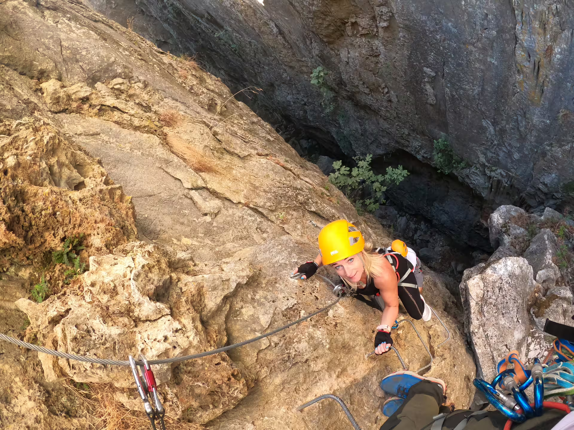 Climber ascending a steep rock face on the Via Ferrata adventure in Benalauría, offering stunning Costa del Sol views.