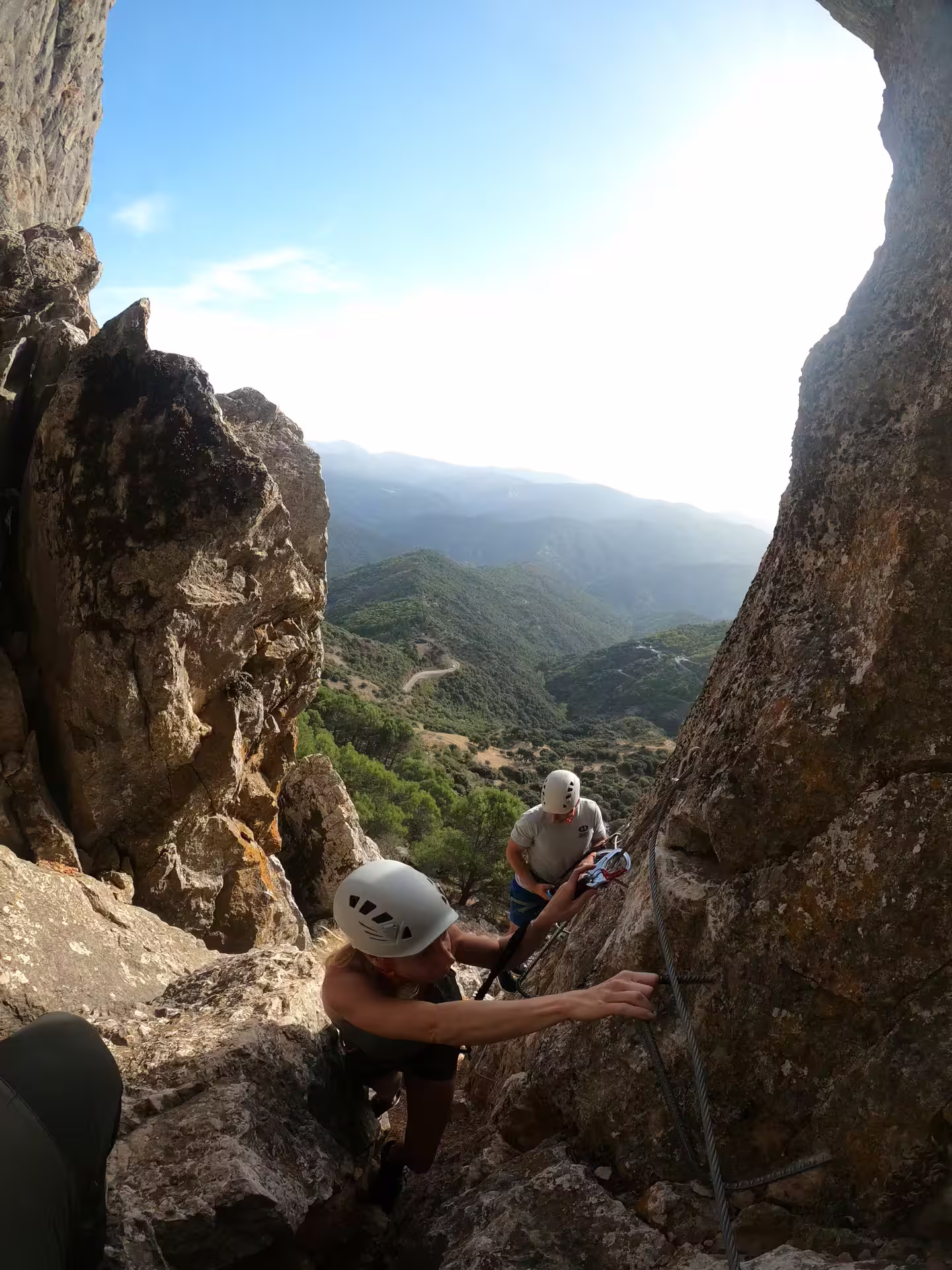 Two climbers navigate a rocky Via Ferrata in Benalauría, offering breathtaking views of the Costa del Sol landscape.