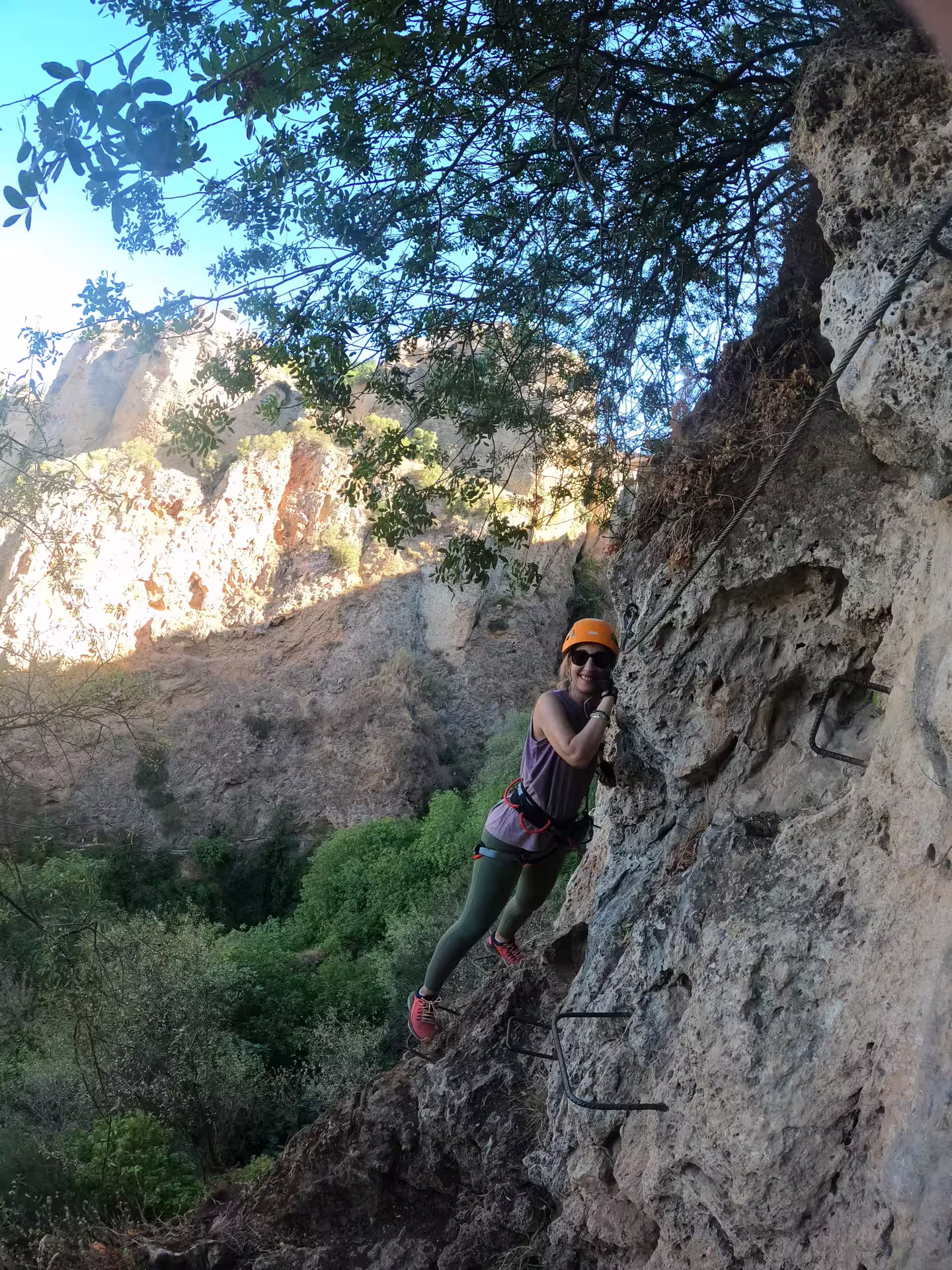 Climber navigating the rugged Via Ferrata Tajo de Ronda route, surrounded by stunning cliffs and lush greenery in Ronda.
