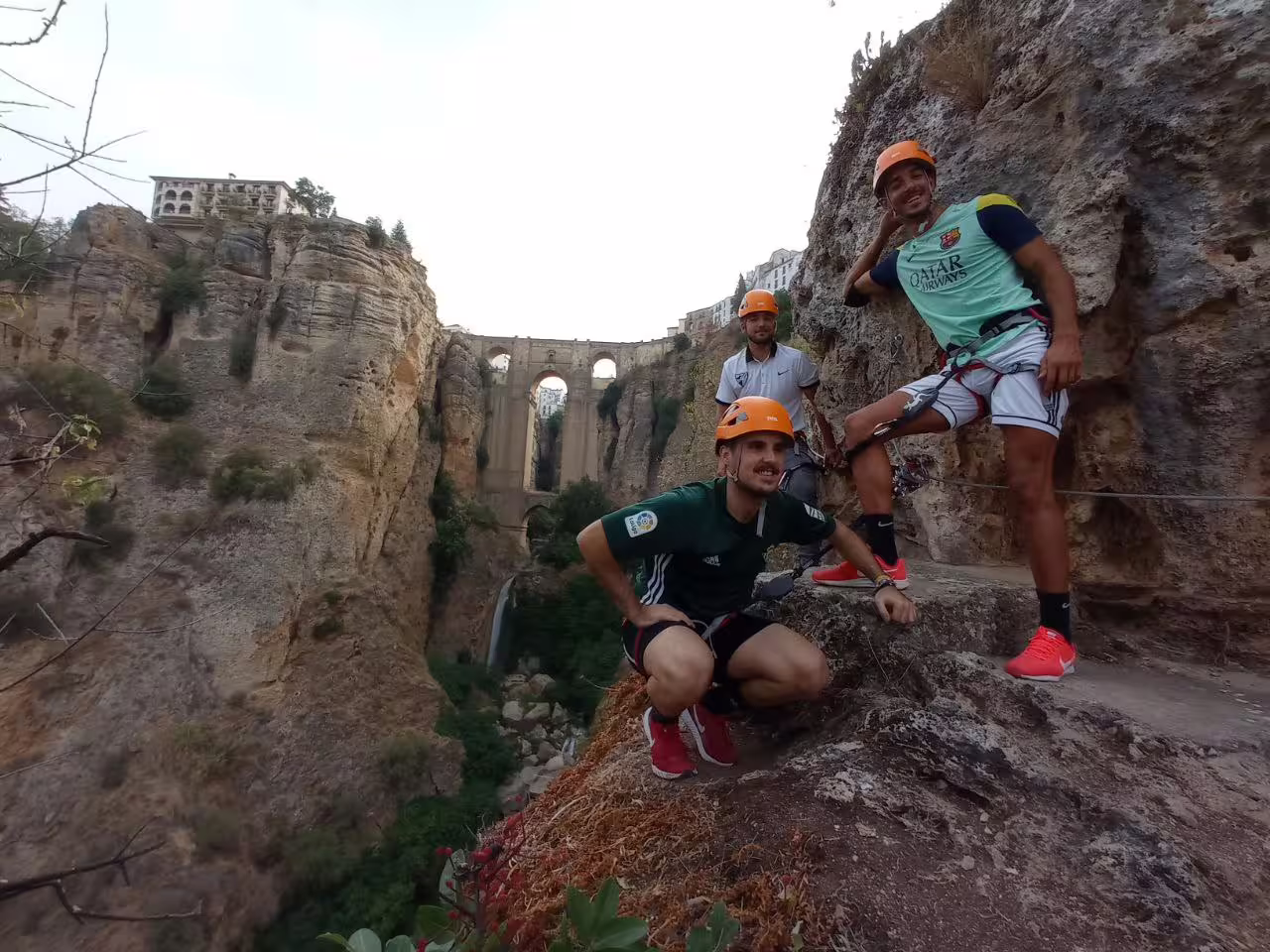 Group of climbers with helmets enjoying the Via Ferrata Tajo de Ronda adventure beside the iconic bridge.