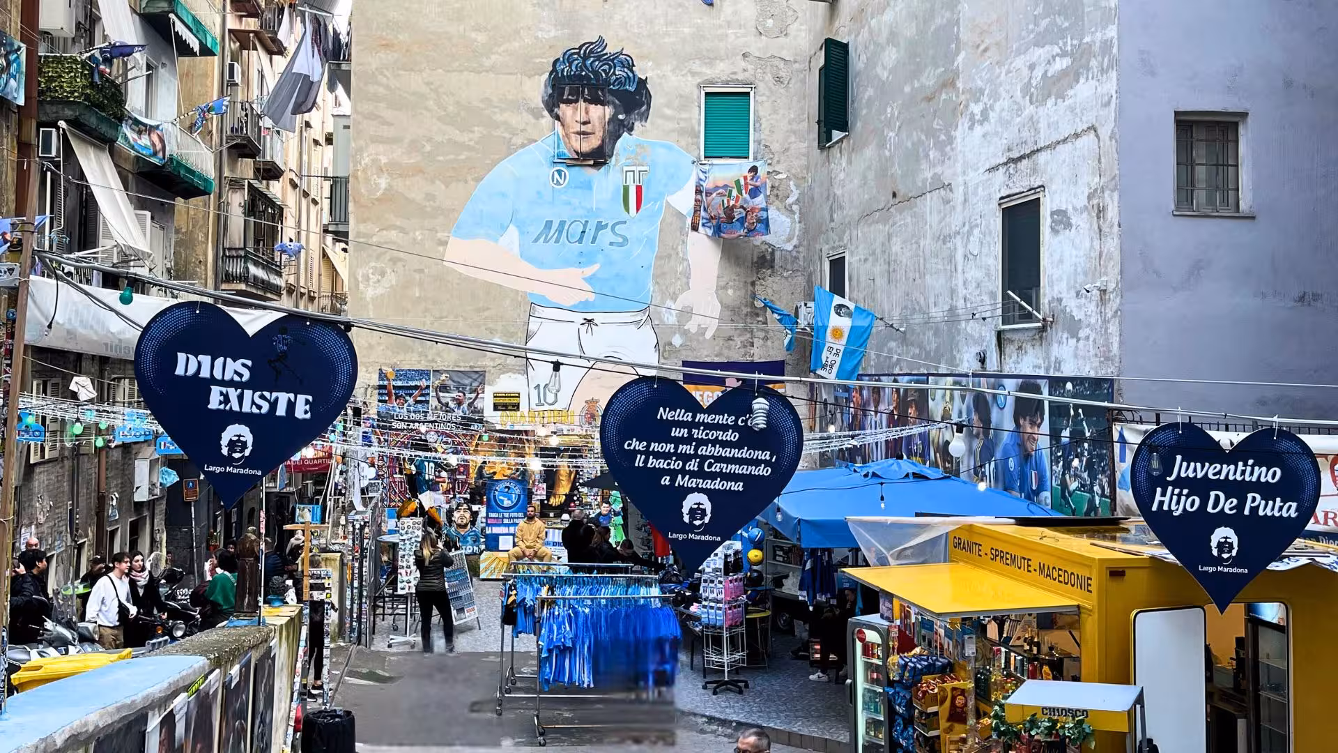 Vibrant street art and bustling shops along Via Toledo in Naples celebrate local culture and Maradona's legacy.