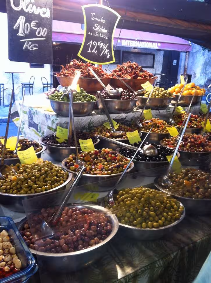 Vibrant market stall showcasing diverse olives and sun-dried tomatoes in Nice, perfect for a colorful excursion.