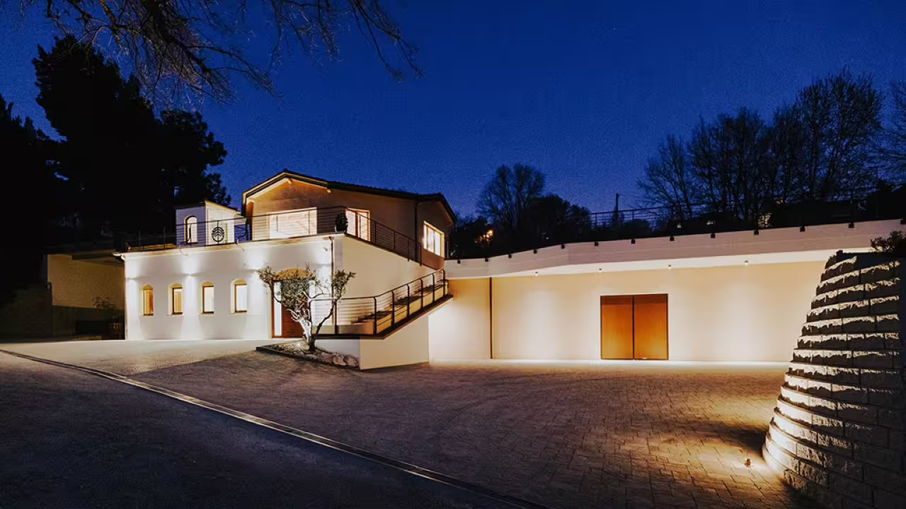 Evening view of Vicari Vini's illuminated winery building, offering a warm welcome to wine enthusiasts in Marche.
