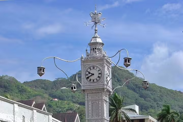 Iconic Victoria Clocktower in Seychelles set against lush green hills, a highlight for island tours.