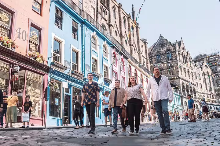 Group of people strolling down vibrant Victoria Street, Edinburgh, with its iconic colorful facades and lively atmosphere.