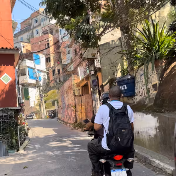 Tourists explore Vidigal Favela's vibrant streets on a guided motorcycle tour with a local resident.